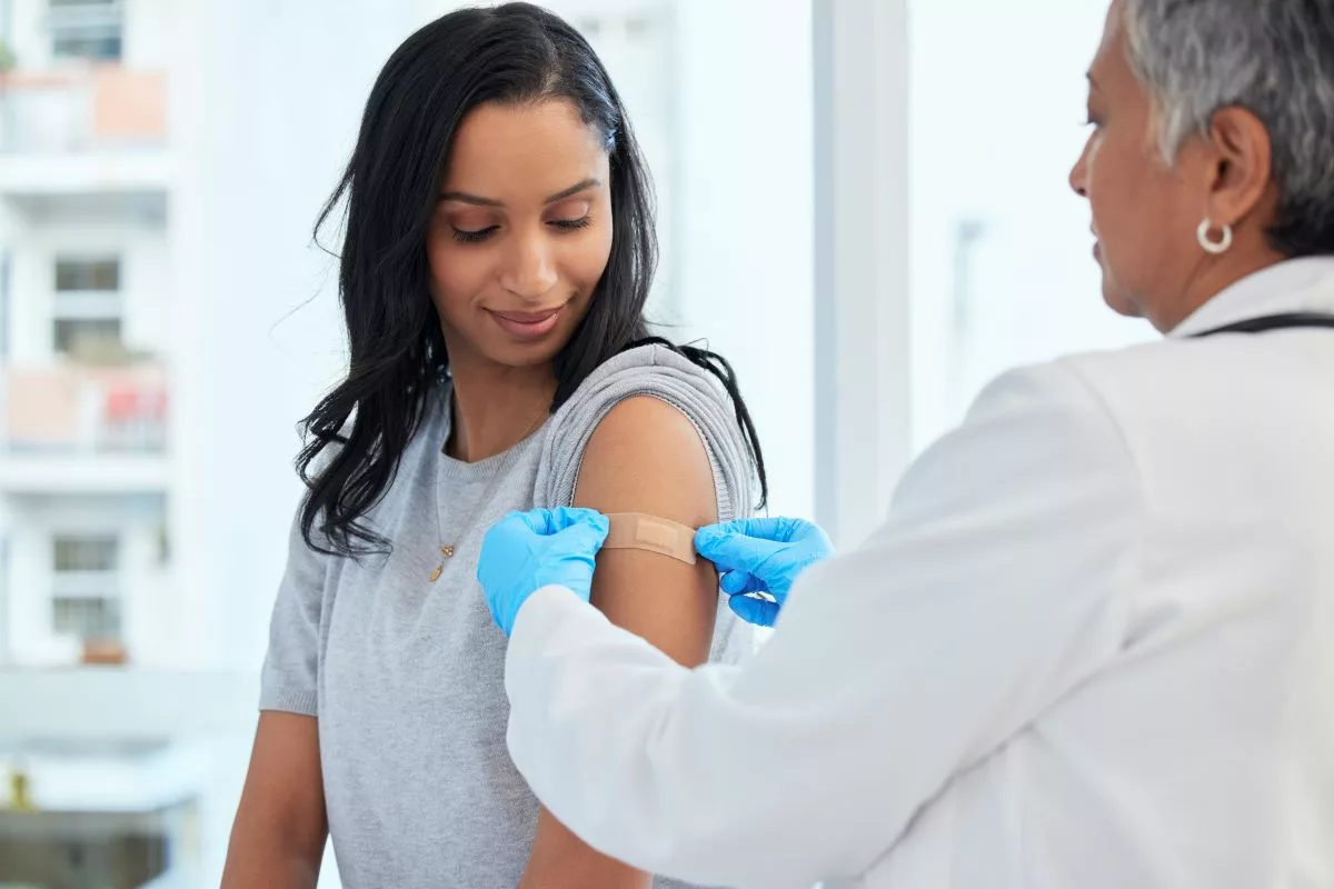 Un médecin met un pansement sur le bras d'une femme après une vaccination.