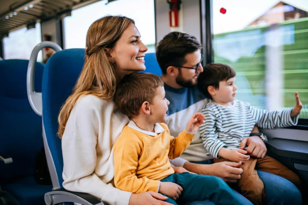 Une famille souriante voyage en train, profitant des aides à la mobilité pour les transports publics.