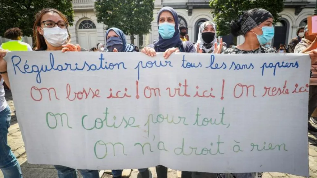 es manifestants revendiquent des droits et une reconnaissance pour les travailleurs sans-papiers contribuant à l'économie belge.