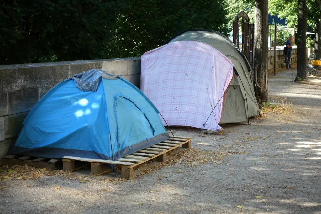 Tentes installées le long d'un mur dans un espace public, symbolisant la situation difficile des personnes sans abri. Les initiatives d'aides aux personnes sans abris en Belgique visent à fournir des solutions d'hébergement et un soutien pour améliorer leurs conditions de vie.