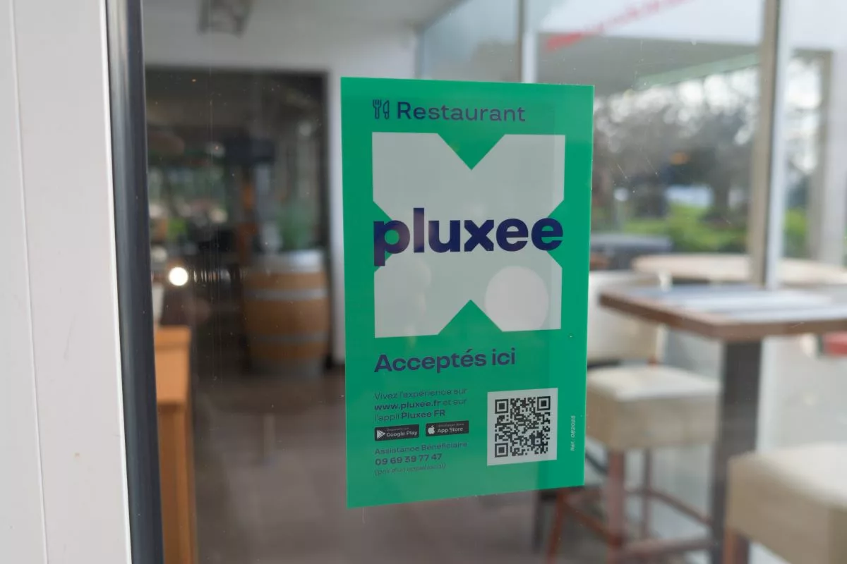 Autocollant vert indiquant que les chèques-repas Pluxee sont acceptés dans ce restaurant en Belgique.