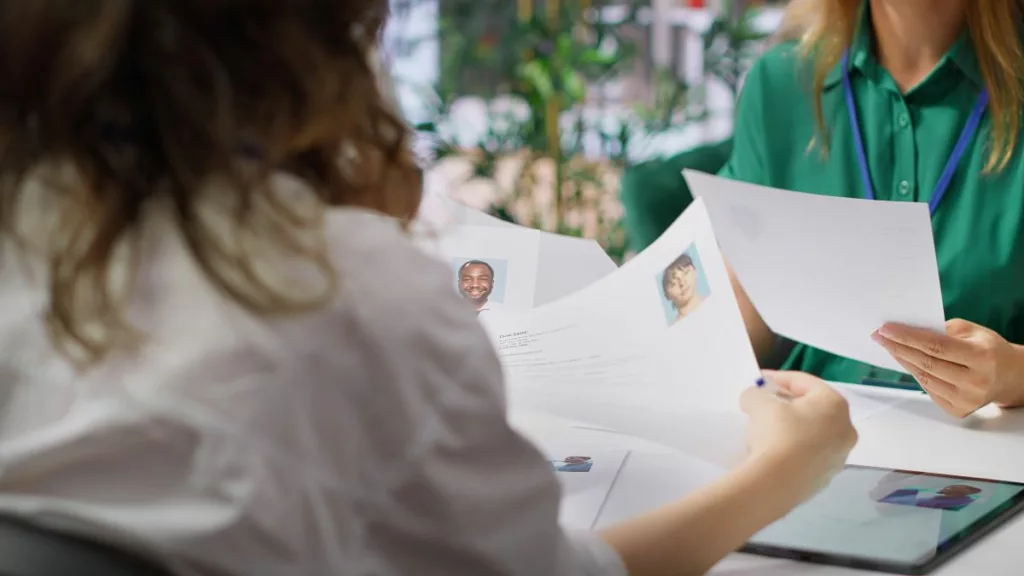 Deux personnes examinant des CV dans un cadre professionnel, illustrant le dispositif Impulsion 12 mois + en Belgique, qui favorise l'emploi des demandeurs d'emploi de longue durée.