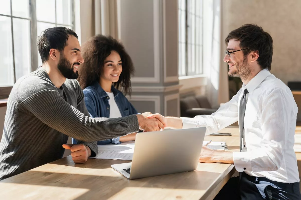 Un couple discutant avec un conseiller financier dans un bureau, illustrant les opportunités offertes par les prêts à taux 0 % en Belgique pour soutenir des projets personnels ou professionnels.