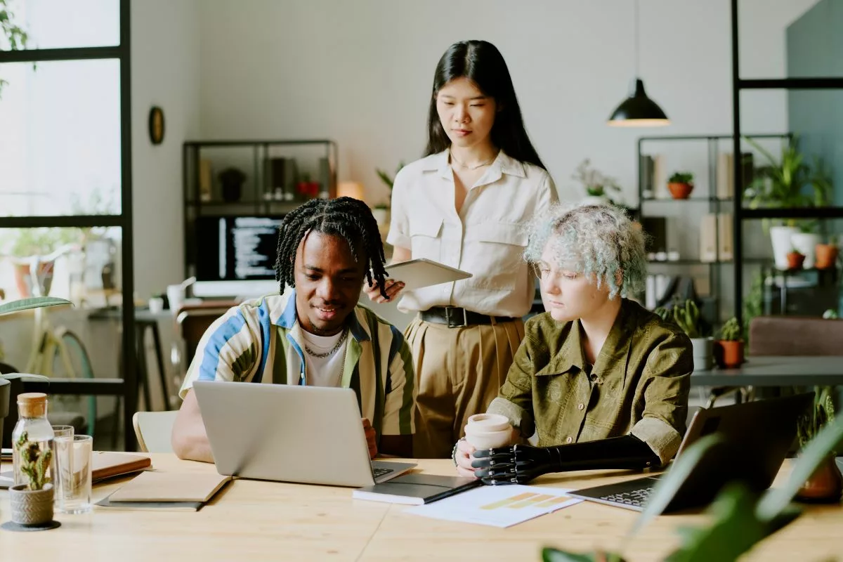 Trois collègues collaborent dans un bureau, illustrant la Prime de reprise du travail en Belgique.