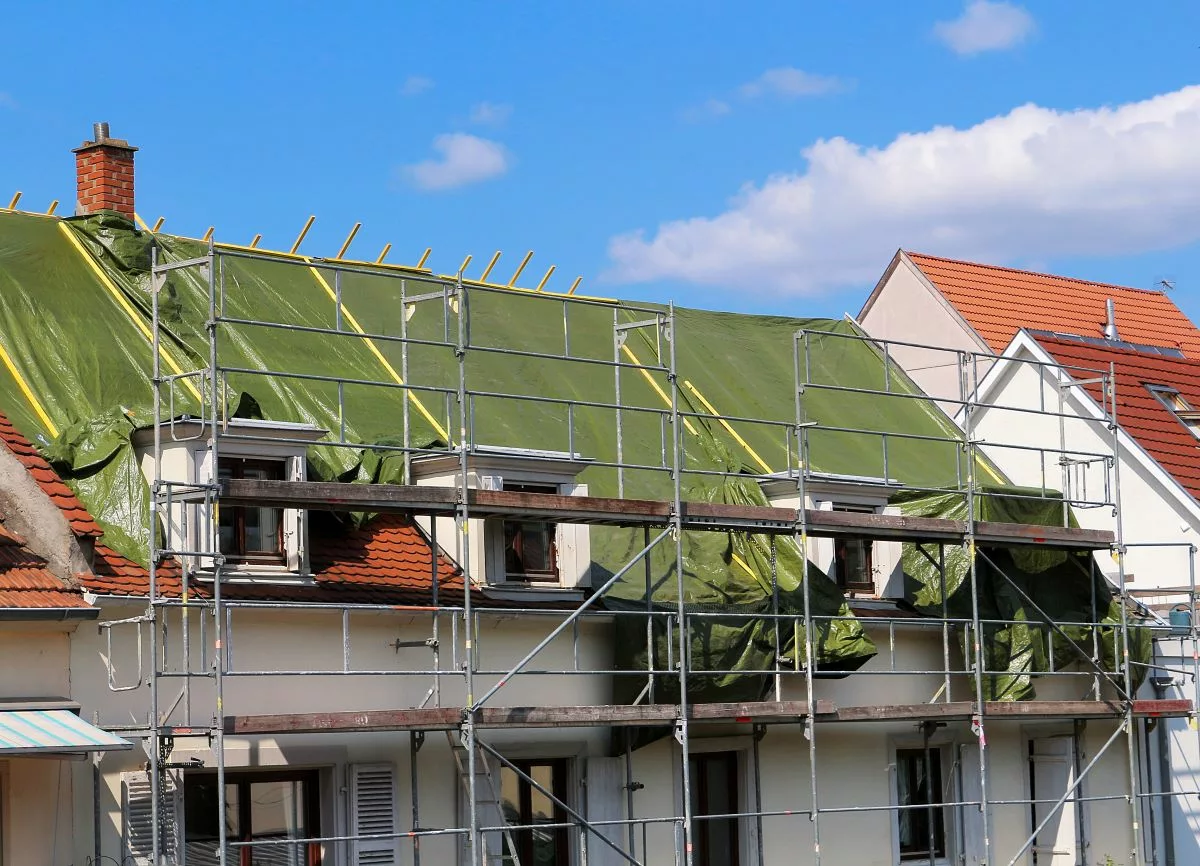 Une maison en rénovation avec des échafaudages et une toiture en travaux, illustrant les aides financières de la prime Toiture et petits travaux sans audit en Wallonie.