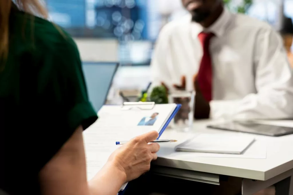 Entretien d'embauche dans une entreprise, avec une recruteuse consultant un CV, illustrant les dispositifs d’aides à l’embauche en Belgique.