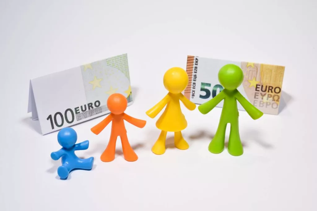Représentation symbolique d'une famille avec des figurines colorées et des billets en euros pour illustrer les allocations familiales en Wallonie en 2025.