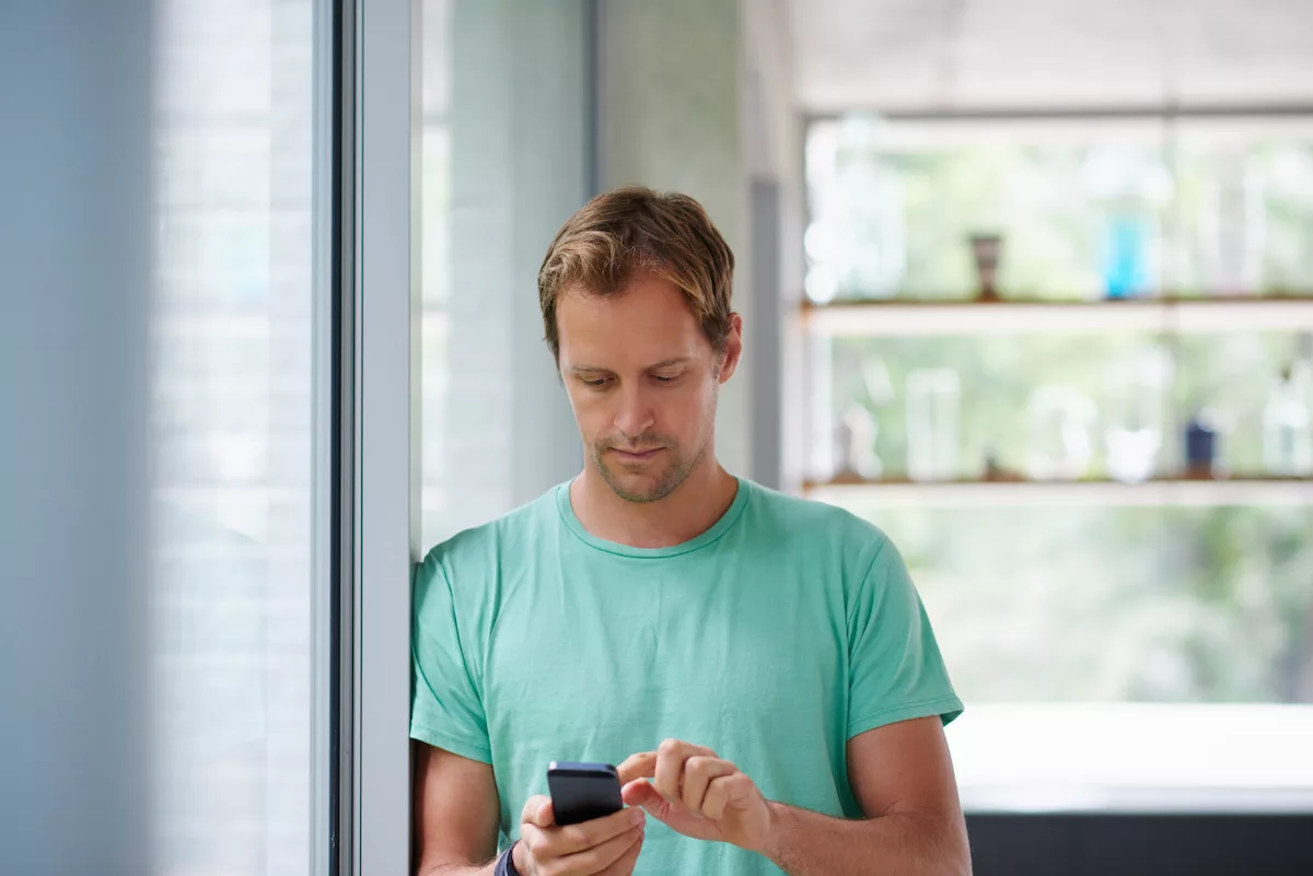 Image d'un homme qui utilise son téléphone portable pour contacter les services de logements sociaux en Belgique.