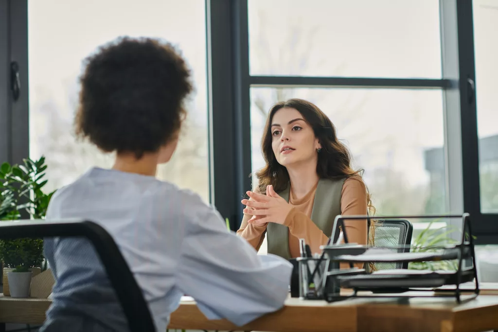 Photo d'une femme à un bureau qui écoute une autre femme, pour illustrer la prise en charge de votre dossier de chômage par la CAPAC