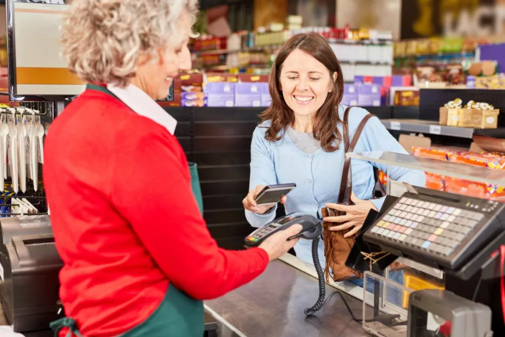 Une cliente règle ses achats à la caisse avec ses éco-chèques électroniques via son téléphone.