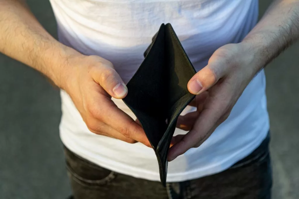 Homme avec portefeuille vide, qui pense à demander l’attestation de non revenu pour profiter d’aide.