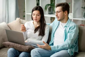 Un jeune couple en train de calculer l'impact des nouvelles règles du RIS sur leur aide sociale.